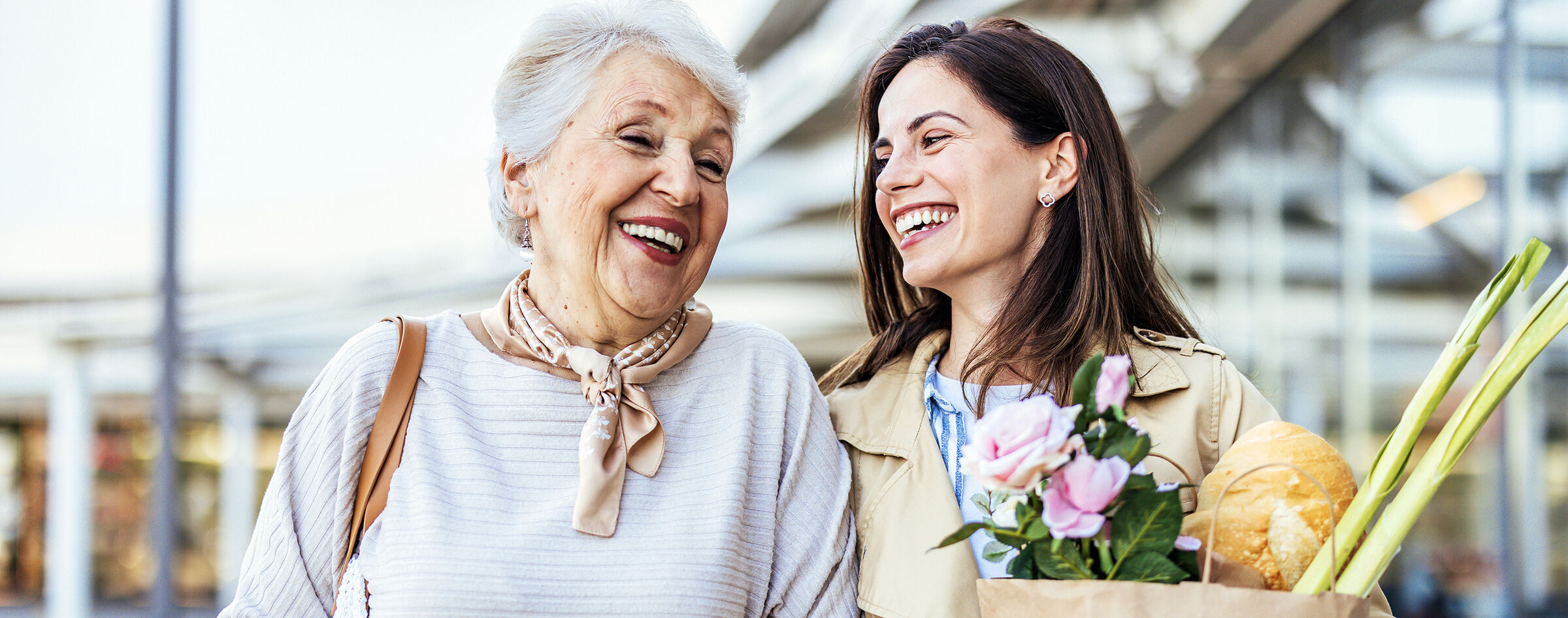 Senior woman and her adult daughter laughing together after a market trip