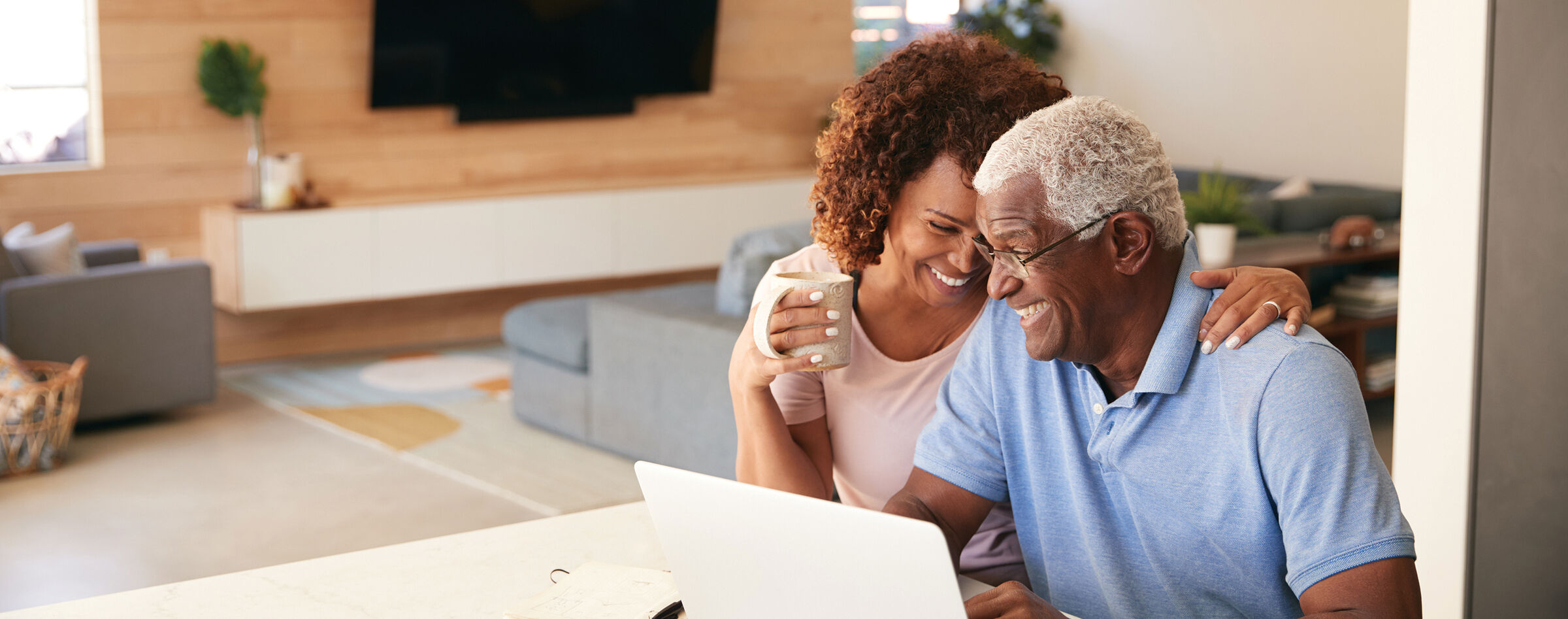 Senior couple sharing a laugh while looking at a laptop at home