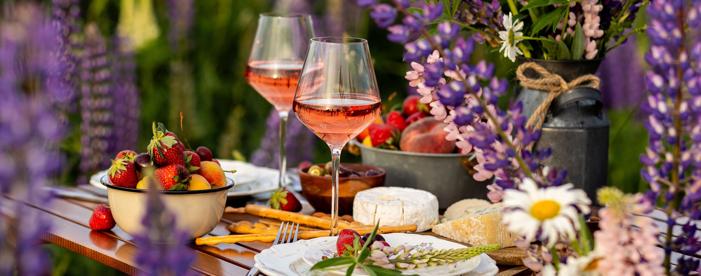 Table set with rosé, fresh fruit and flowers for a garden gathering