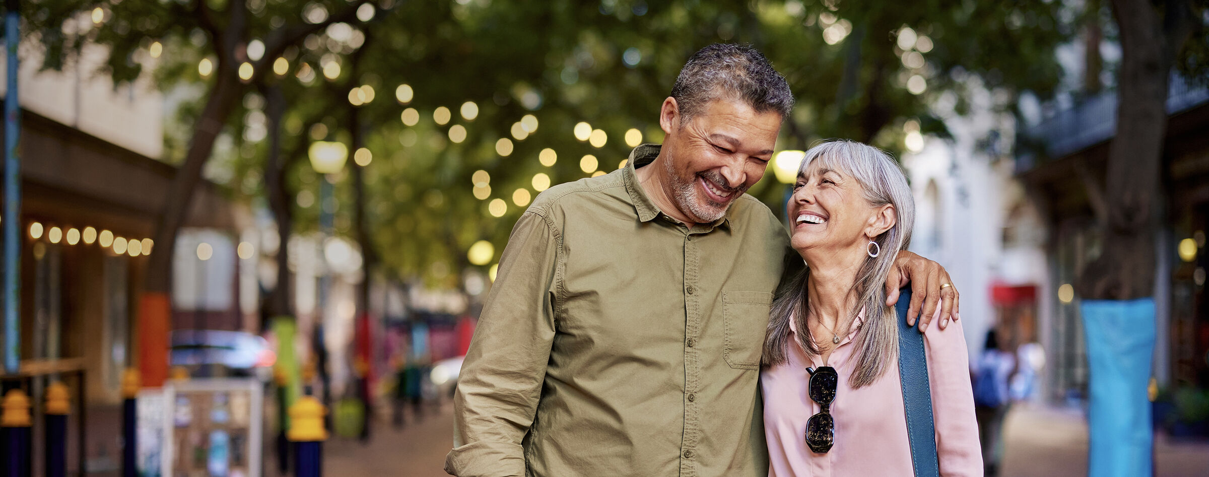 Active senior couple walking arm in arm under string lights