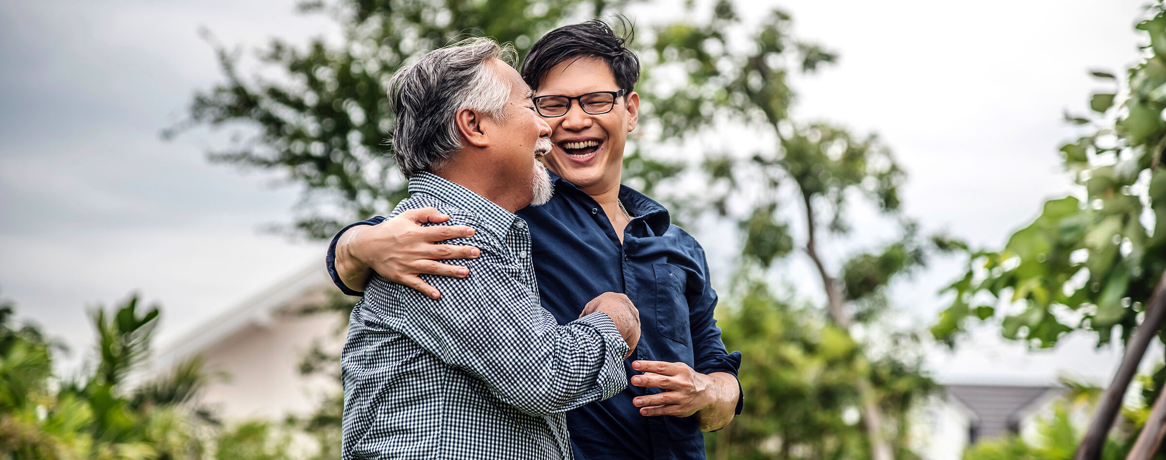 Senior father and adult son embracing outdoors