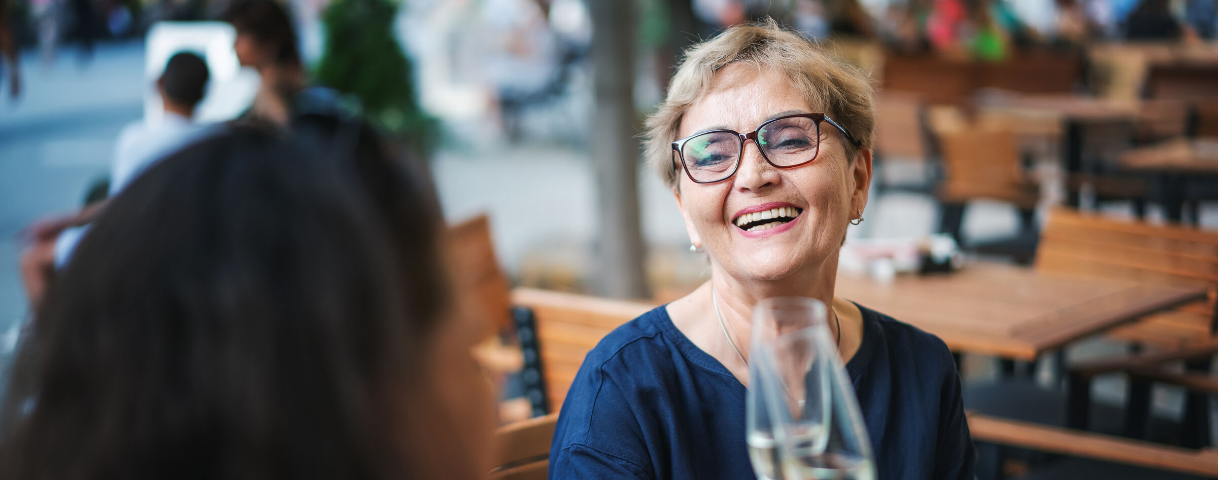 Senior woman smiling and raising a glass at an outdoor restaurant