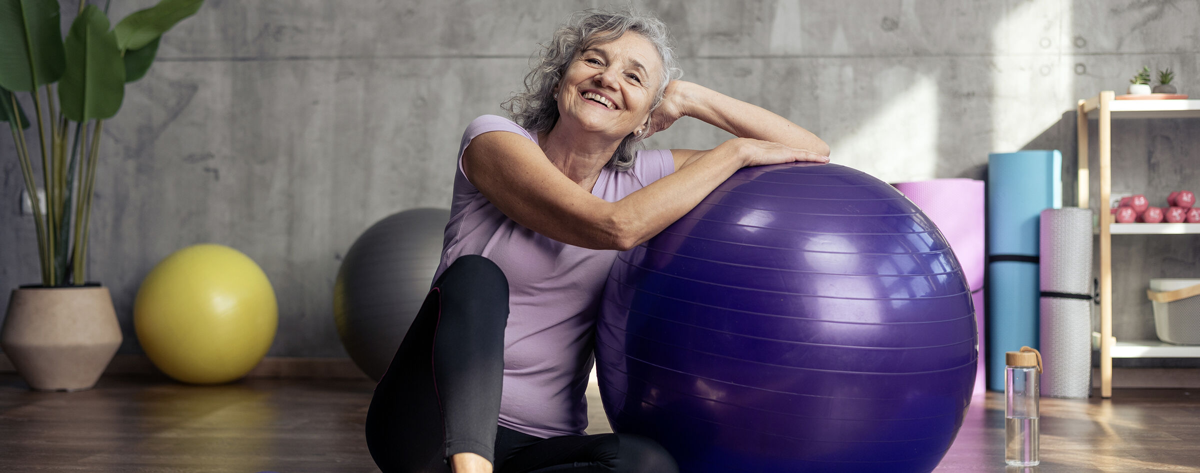 Senior woman stretching with an exercise ball in a wellness studio